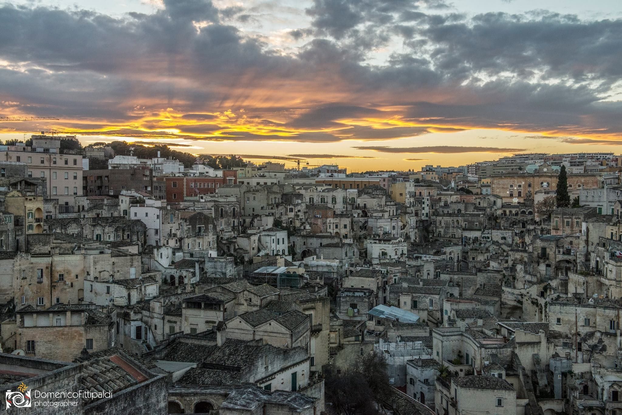 A densely packed urban area with historic buildings and a sunset sky.