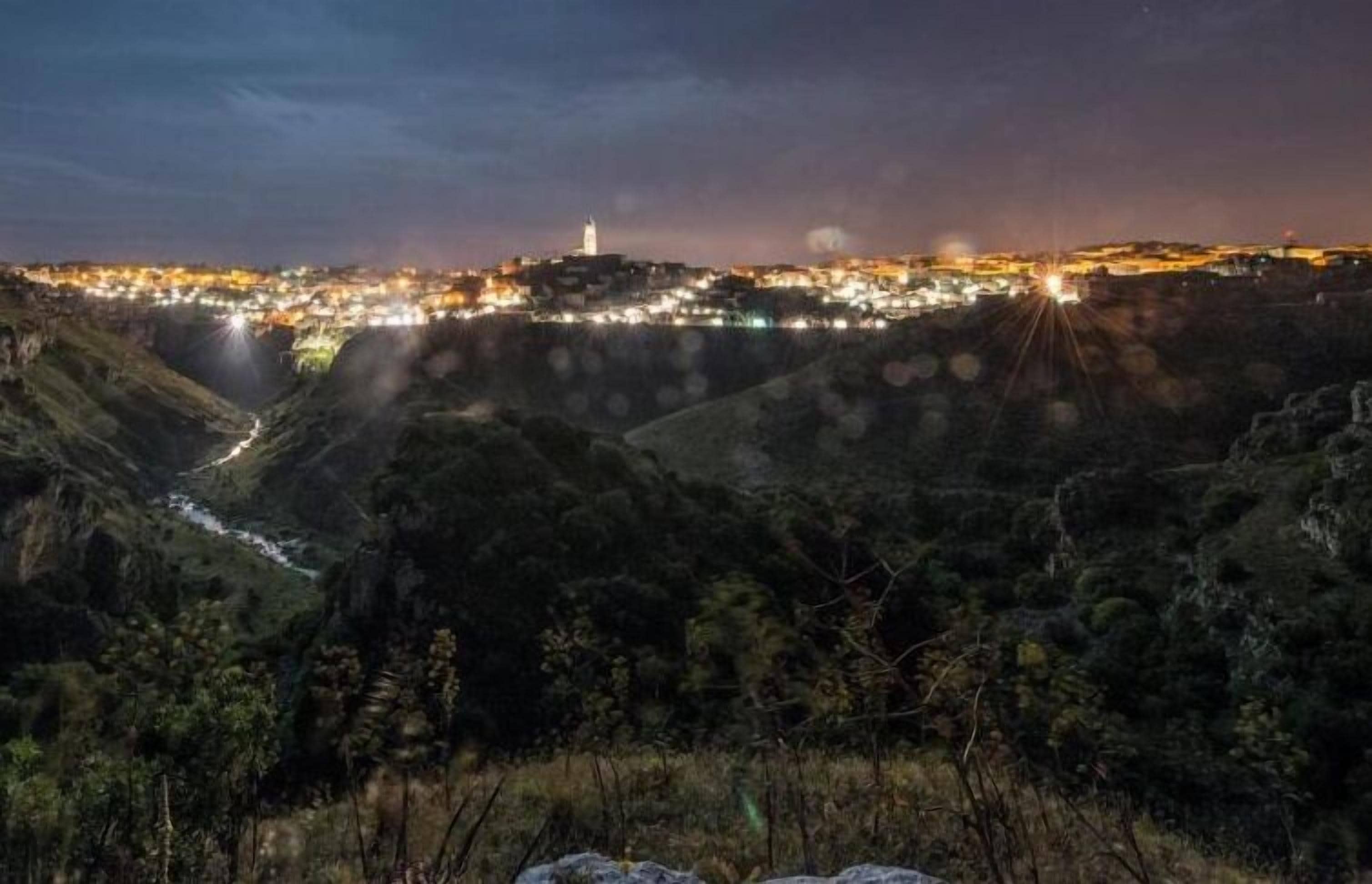 Vista noturna de uma cidade com uma torre imponente e um rio.