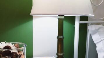 Una mesa con una lámpara blanca, un tarro de cristal con flores secas y una vela.