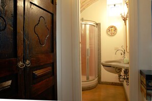 A bathroom with a wooden door, a shower, and a sink with a decorative mirror. - Villino Corbelli (Rome)