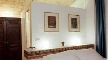 A room with a bed, a wooden wardrobe, and two framed pictures on the wall.