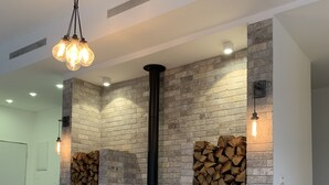 Un salon moderne doté d’une cheminée intégrée, de bûches de bois et d’un luminaire suspendu.