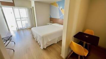 Habitación de hotel con cama, escritorio, silla y vistas al exterior.