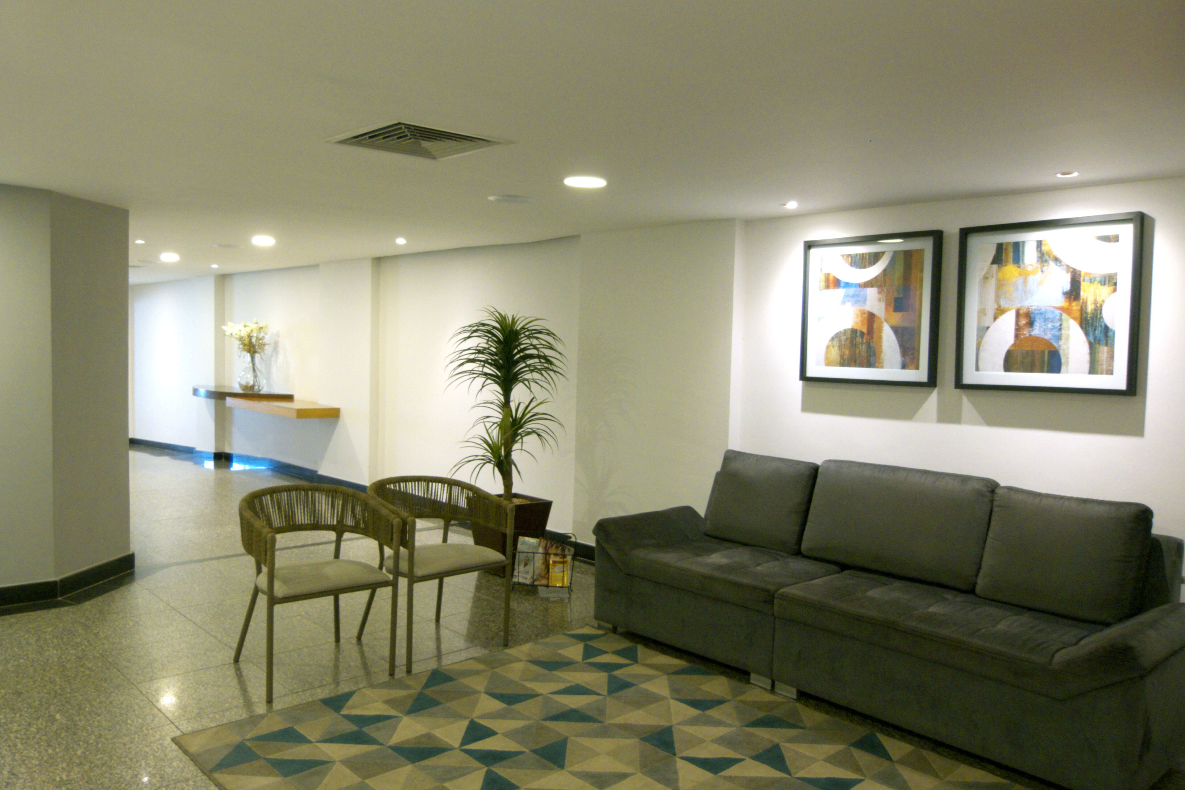 A reception area with a sofa, chairs, a plant, and artwork on the wall.