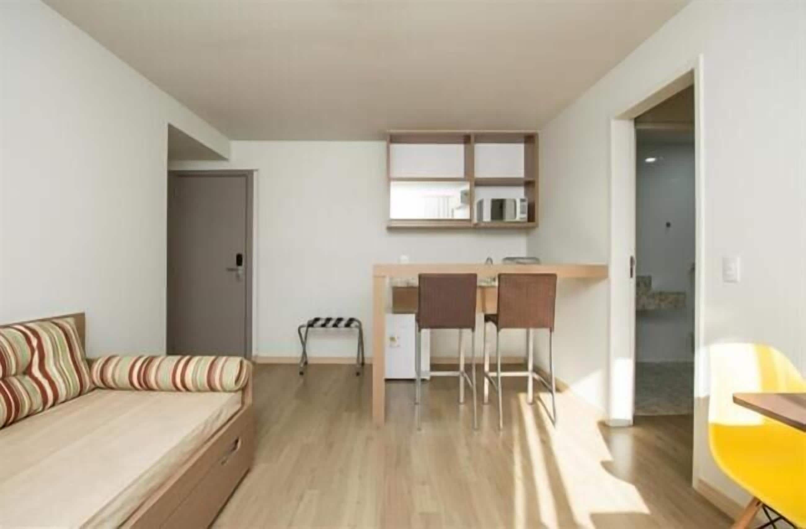 A compact living space with a sofa, a small kitchenette, and a dining area.