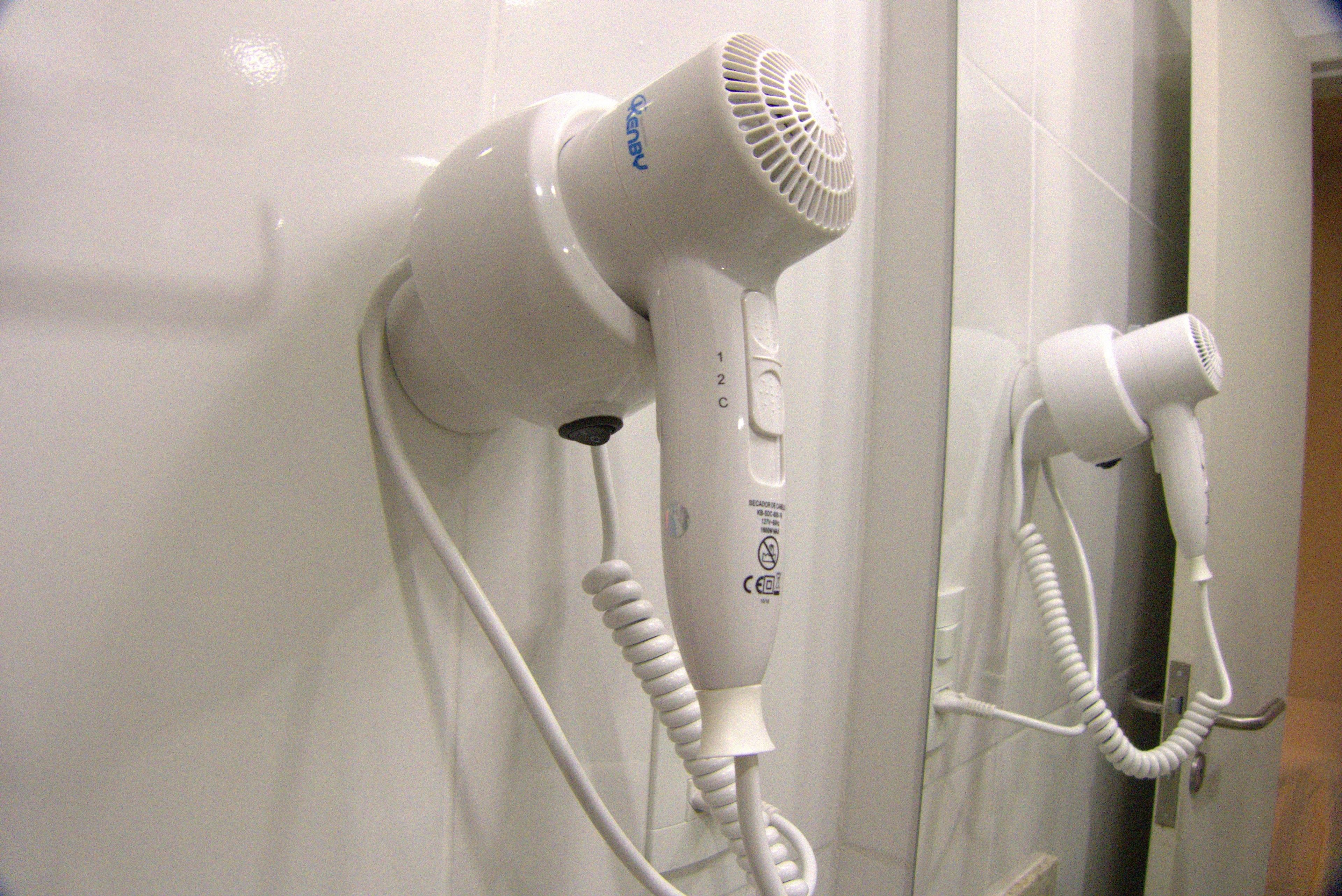 Two hair dryers mounted on a wall.