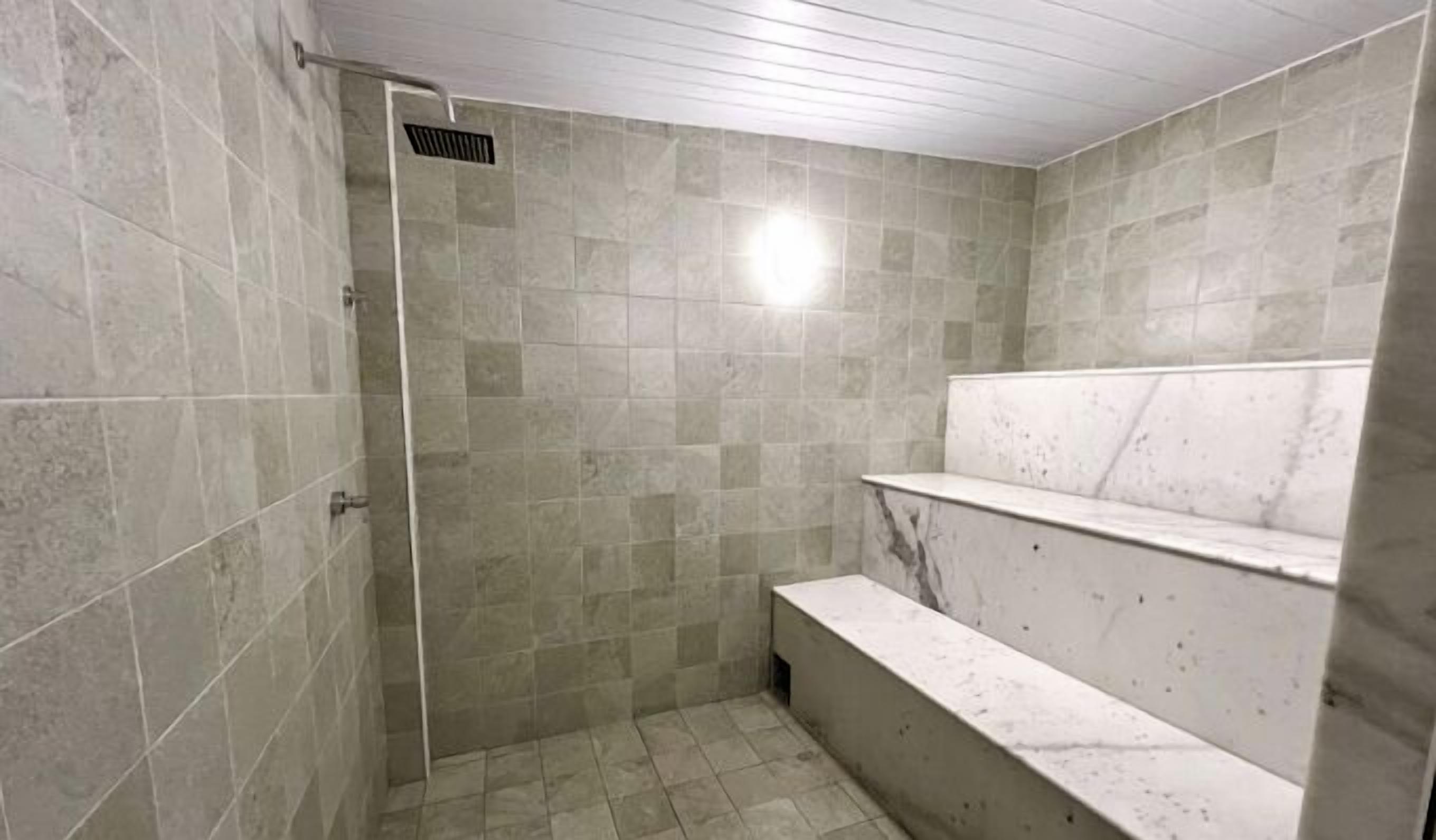 A shower area with tiled walls and a bench.