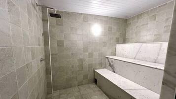 A shower area with tiled walls and a bench.