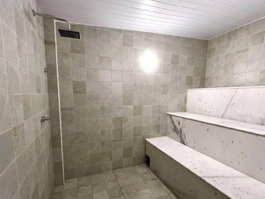 A shower area with tiled walls and a bench.