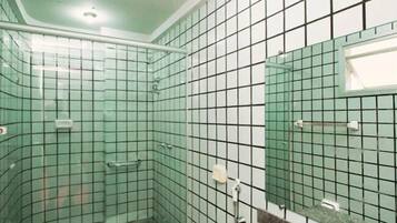 A bathroom with a tiled floor, a shower area, a sink with a mirror, and a toilet.