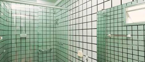 Une salle de bain avec un sol carrelé, un espace douche, un lavabo avec un miroir et des toilettes.