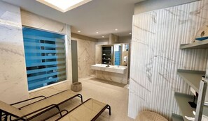 A modern bathroom with a marble vanity, a large window with blinds, and a seating area with a bench.