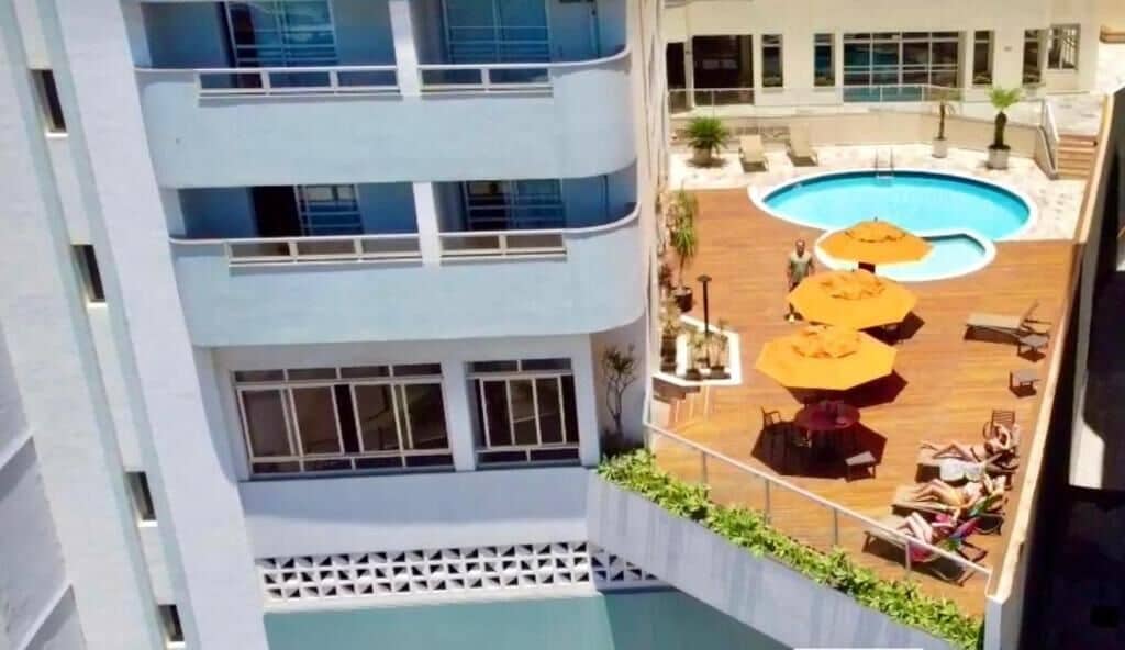 Un edificio de varios pisos con una piscina en la azotea, zona de estar al aire libre y vistas a la piscina.