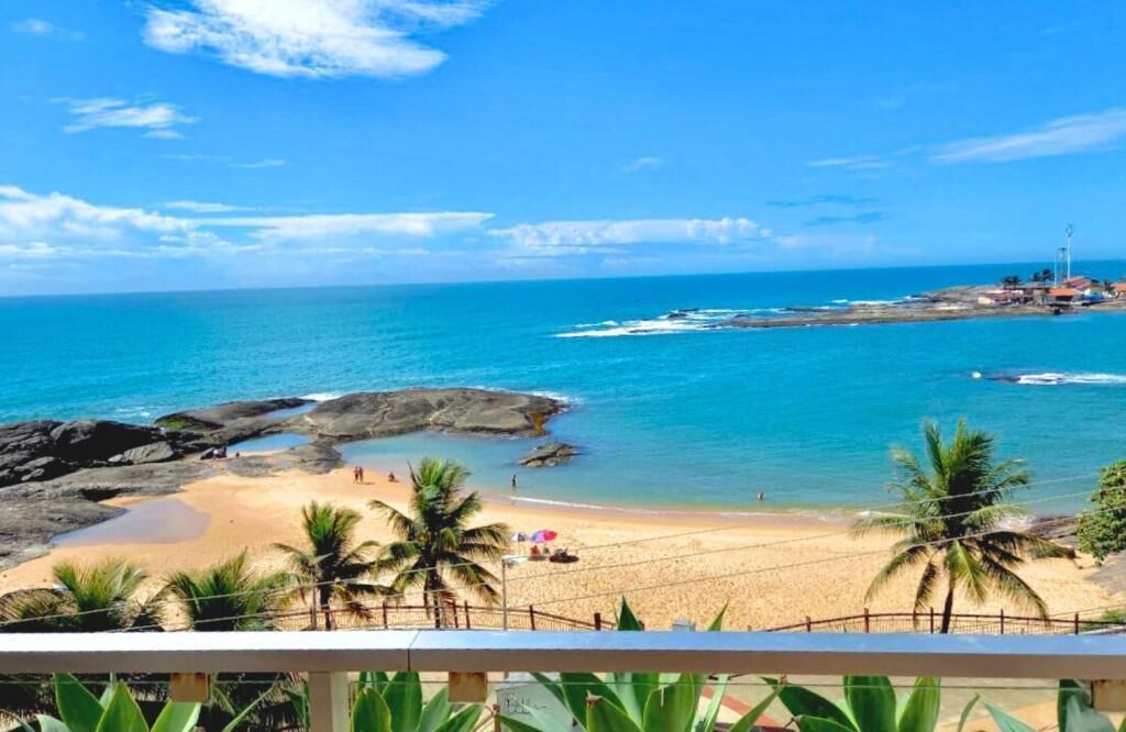 A beach with clear blue water, rocky areas, and palm trees.