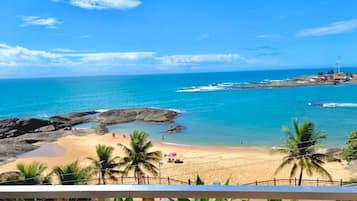 A beach with clear blue water, rocky areas, and palm trees.