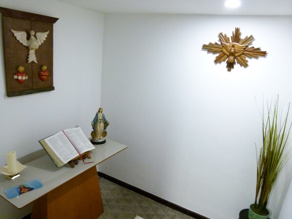 A reception desk with a book, a statue, and wall decorations including a dove and a sunburst. - Hotel Atlântico (Guarapari)