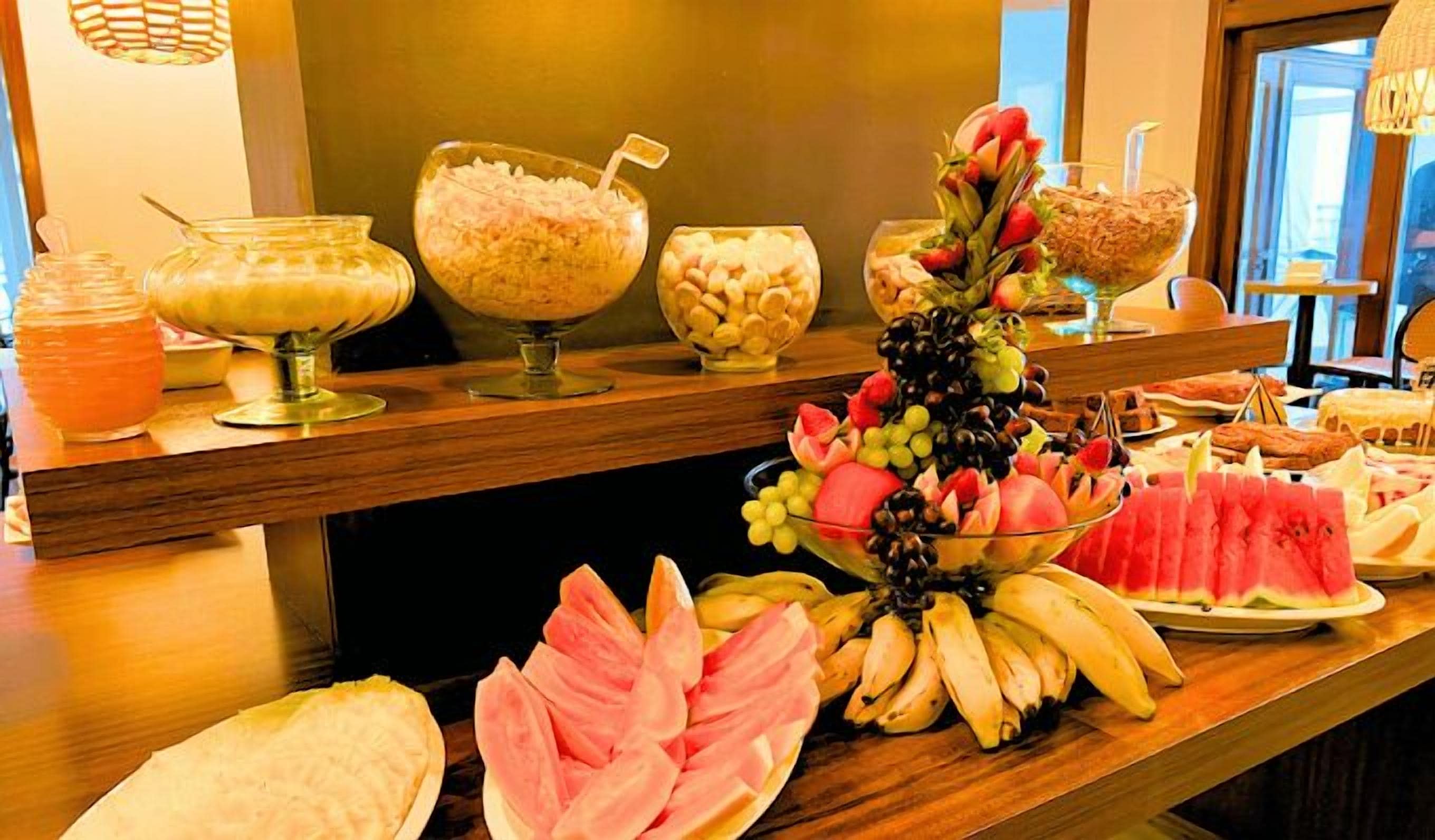 Un bufé con distintos alimentos, entre ellos frutas, nueces y una decoración central.