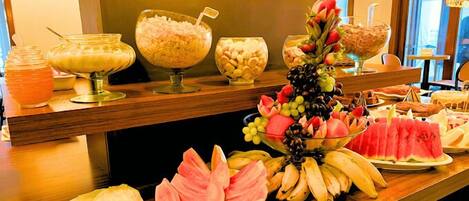 A buffet with various food items including fruits, nuts, and a decorative centerpiece.