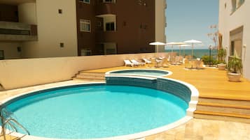 Una piscina al aire libre, sillones reclinables de piscina