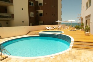 Una piscina al aire libre, sillones reclinables de piscina