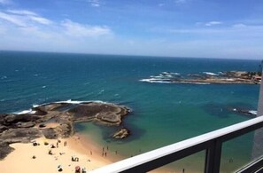 Une vue panoramique sur la côte, prise depuis un point de vue élevé, qui inclut une plage, l’océan et des formations rocheuses.