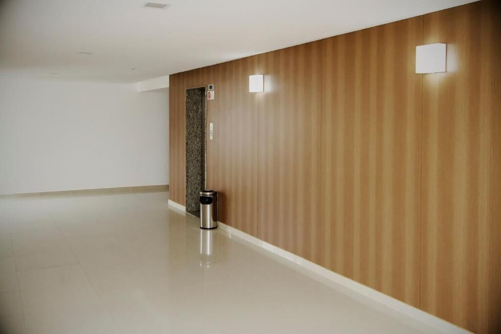 Un corridoio con parete in legno, un cestino e una porta con il cartello 'vietato fumare'.