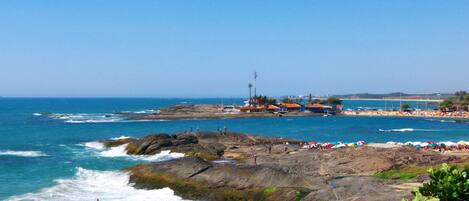 A coastal area with rocky terrain, a beach, and a clear sky.