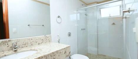 A bathroom with a marble sink, a toilet, and a glass-enclosed shower.