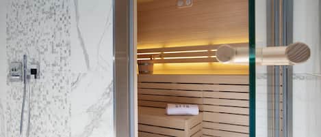 En moderne sauna med træbænke og en glasdør, et bruseområde med flisebeklædt væg og en marmorgulv.