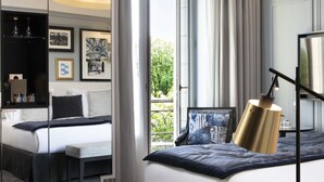 Habitación de hotel moderna con una cama grande, una mesita de noche, un espejo y vistas al exterior.