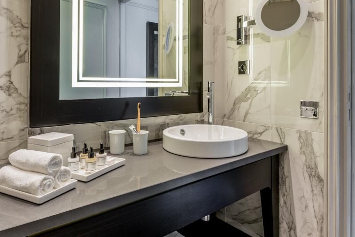 Un baño moderno con un espejo grande, un lavabo redondo y toallas ordenadamente dobladas.
