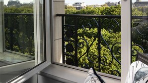 Un balcón con vistas a la Torre Eiffel, barandilla de hierro forjado y cojines estampados.