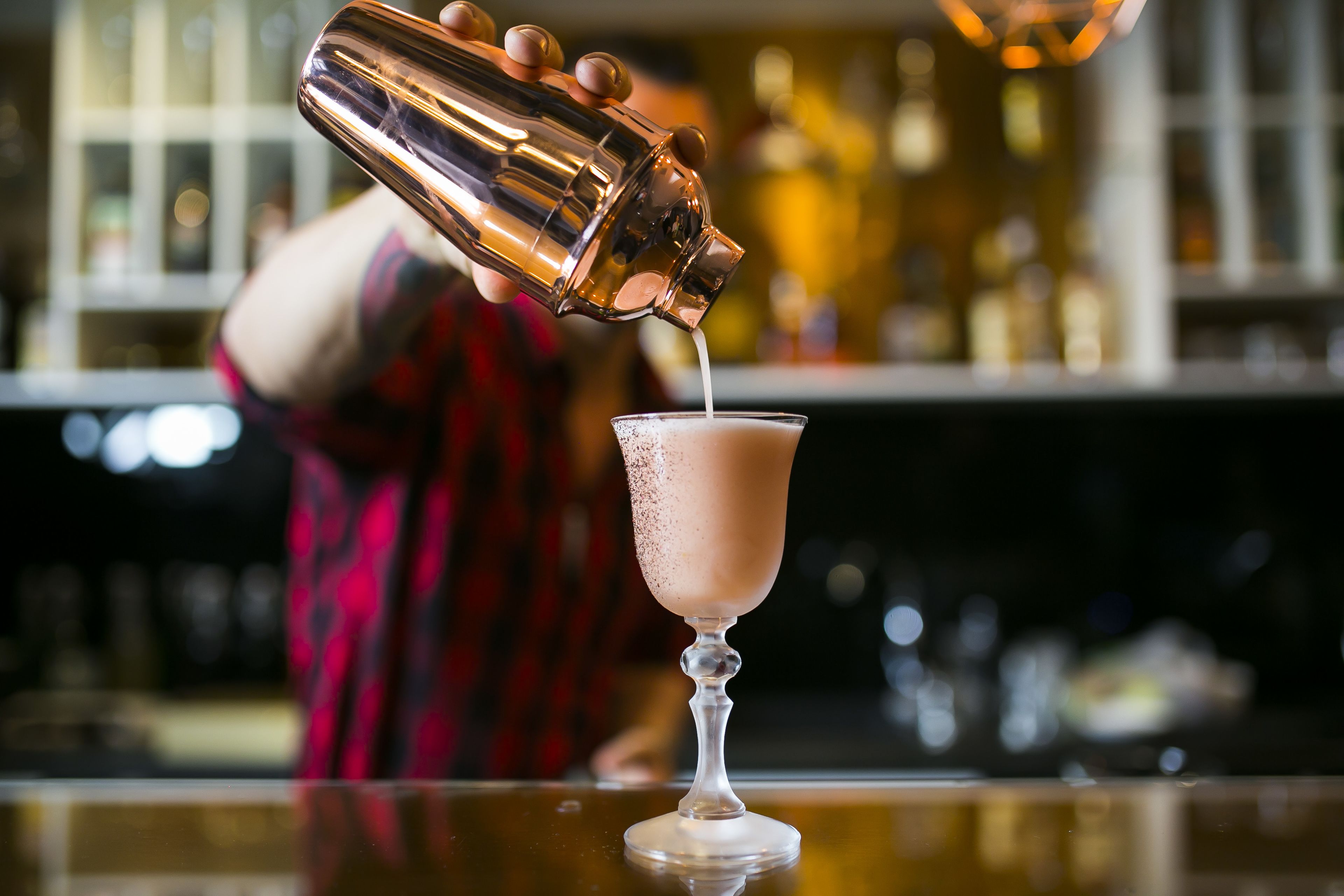 A bartender pouring a drink into a glass.