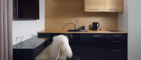 A modern kitchen with a wooden countertop, black cabinets, a built-in stove, and a sink with a coffee maker.