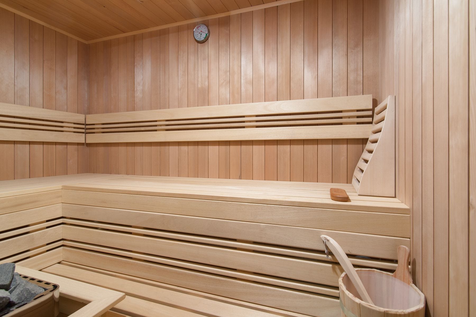 A sauna with wooden benches and a wooden bucket.