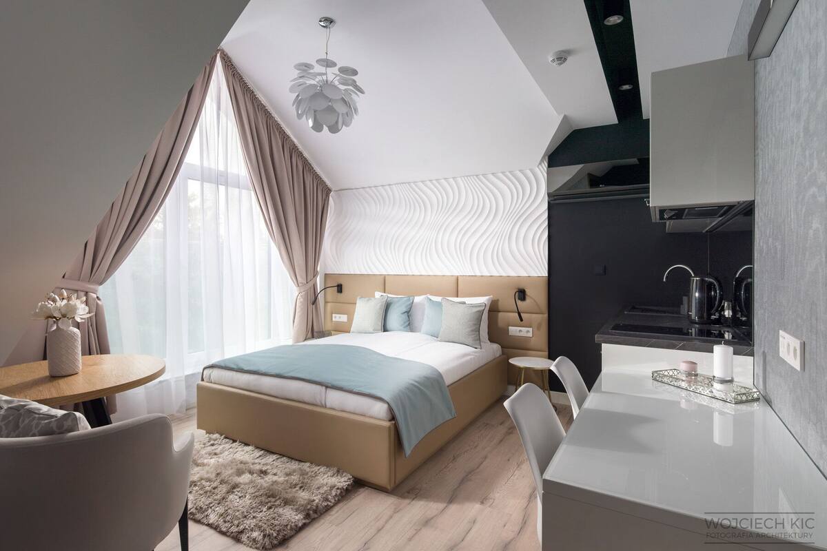 Ein modernes Hotelzimmer mit Bett, Nachttisch und einer Küchenzeile.