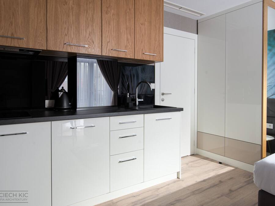 A modern kitchen with white cabinets, a black countertop, and a built-in oven.
