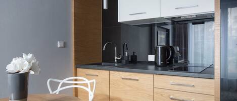A modern kitchen with wooden cabinets, a black countertop, and a stainless steel range hood.