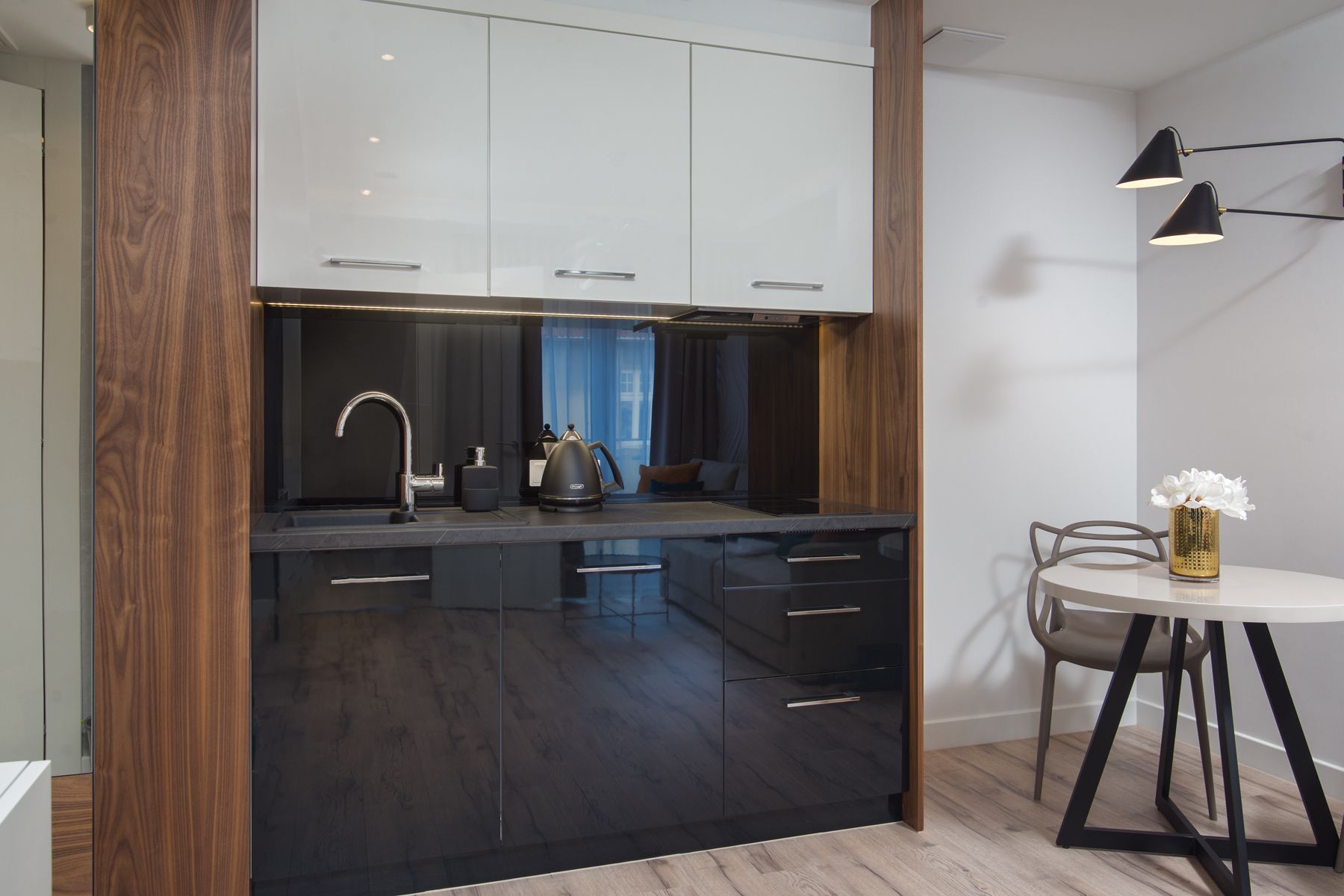 A modern kitchen with dark wood cabinets, a black countertop, and a dining area with a round table and chairs.