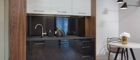 A modern kitchen with dark wood cabinets, a black countertop, and a dining area with a round table and chairs.