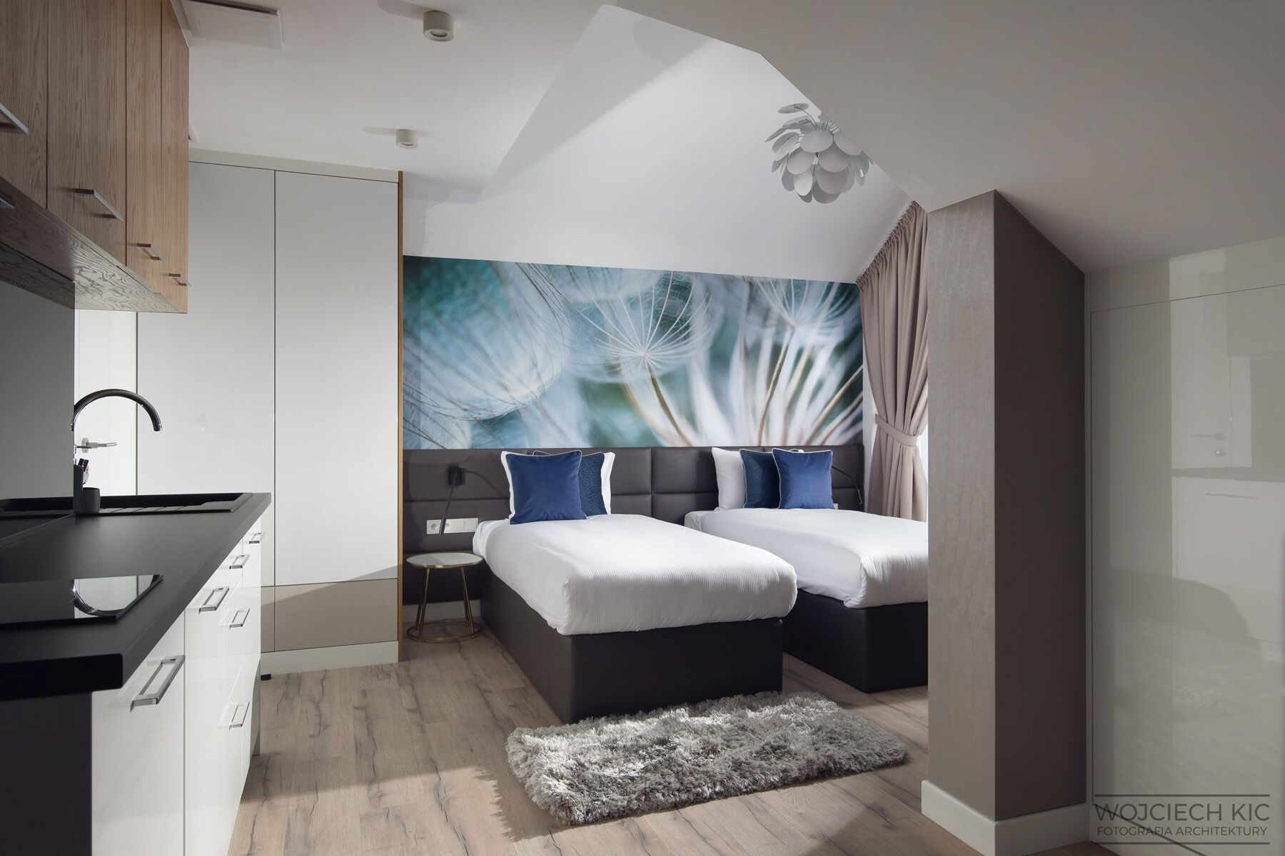 A modern bedroom with two beds, a large window, and a wall mural.