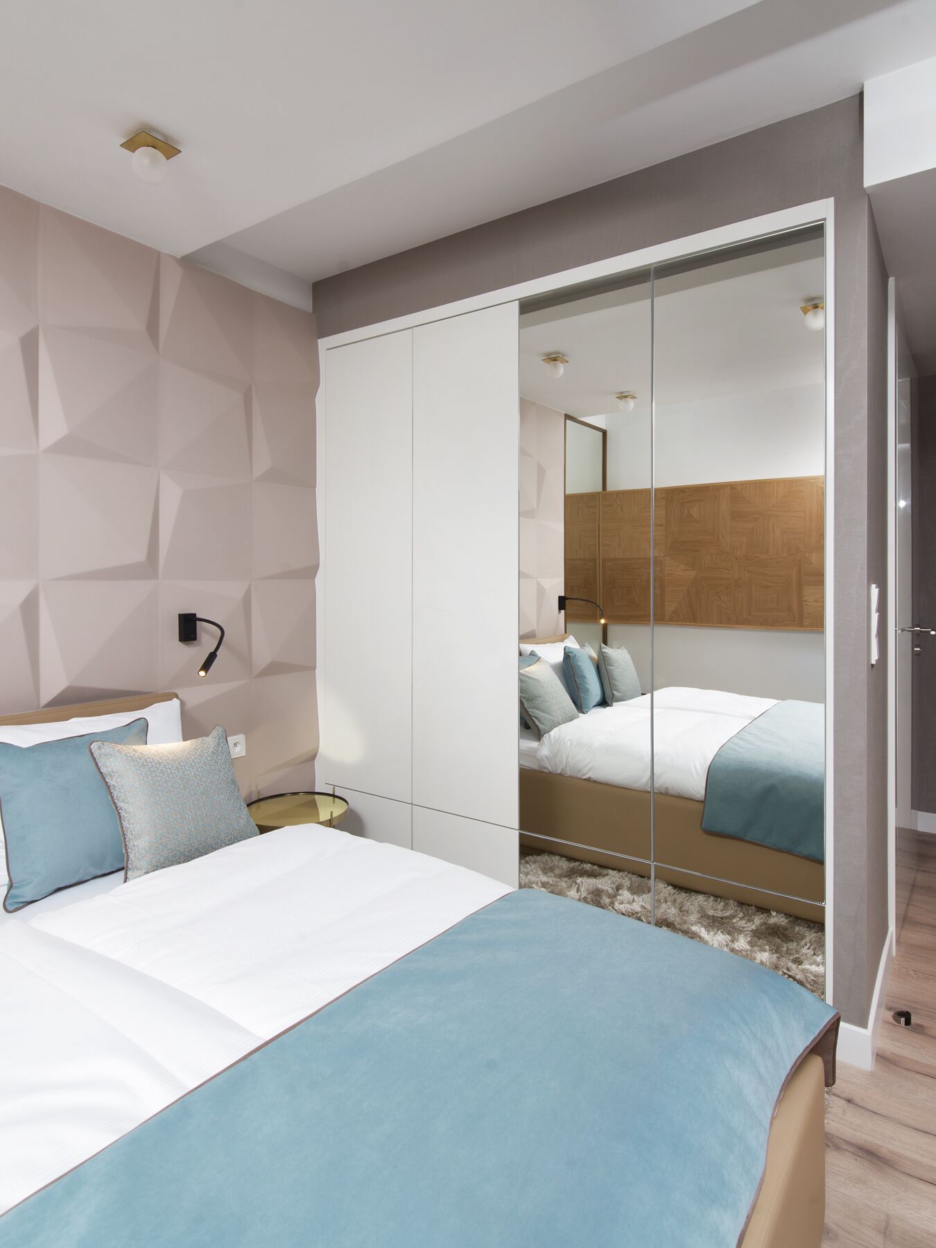 A modern bedroom with a bed, bedside table, and a wardrobe with a mirror.