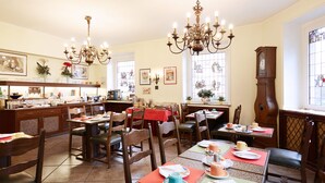 A dining area with multiple tables and chairs, a chandelier, and a large clock on the wall. - Hotel Doria (Düsseldorf)