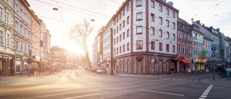 A street view with a tram line, buildings with commercial establishments, and a clear sky.