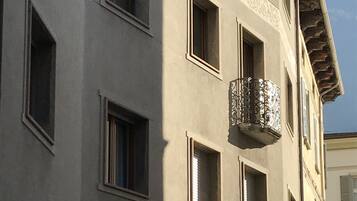 Un edificio a più piani con un balcone, finestre ad arco e un lampione.