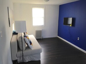 A room with a white sofa, a white lamp, a blue wall, and a window with blinds.