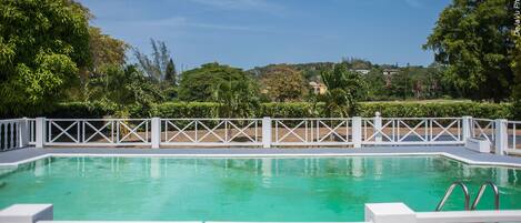 Una piscina al aire libre, sillones reclinables de piscina