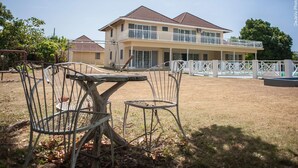 A two-story house with a balcony, a fenced yard, and a table with chairs. - Breezy Shores at Cardiff Hall (Runaway Bay)
