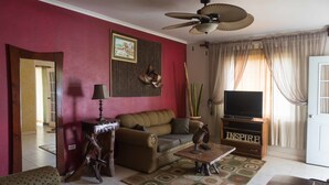 A living room with a sofa, a coffee table, a TV stand, and a ceiling fan. - Wellington Cove (Kingston)