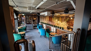 A modern interior with a staircase leading to a lower level, featuring a bar area with blue chairs and a flower arrangement. - House Hotel Belfast (Belfast)
